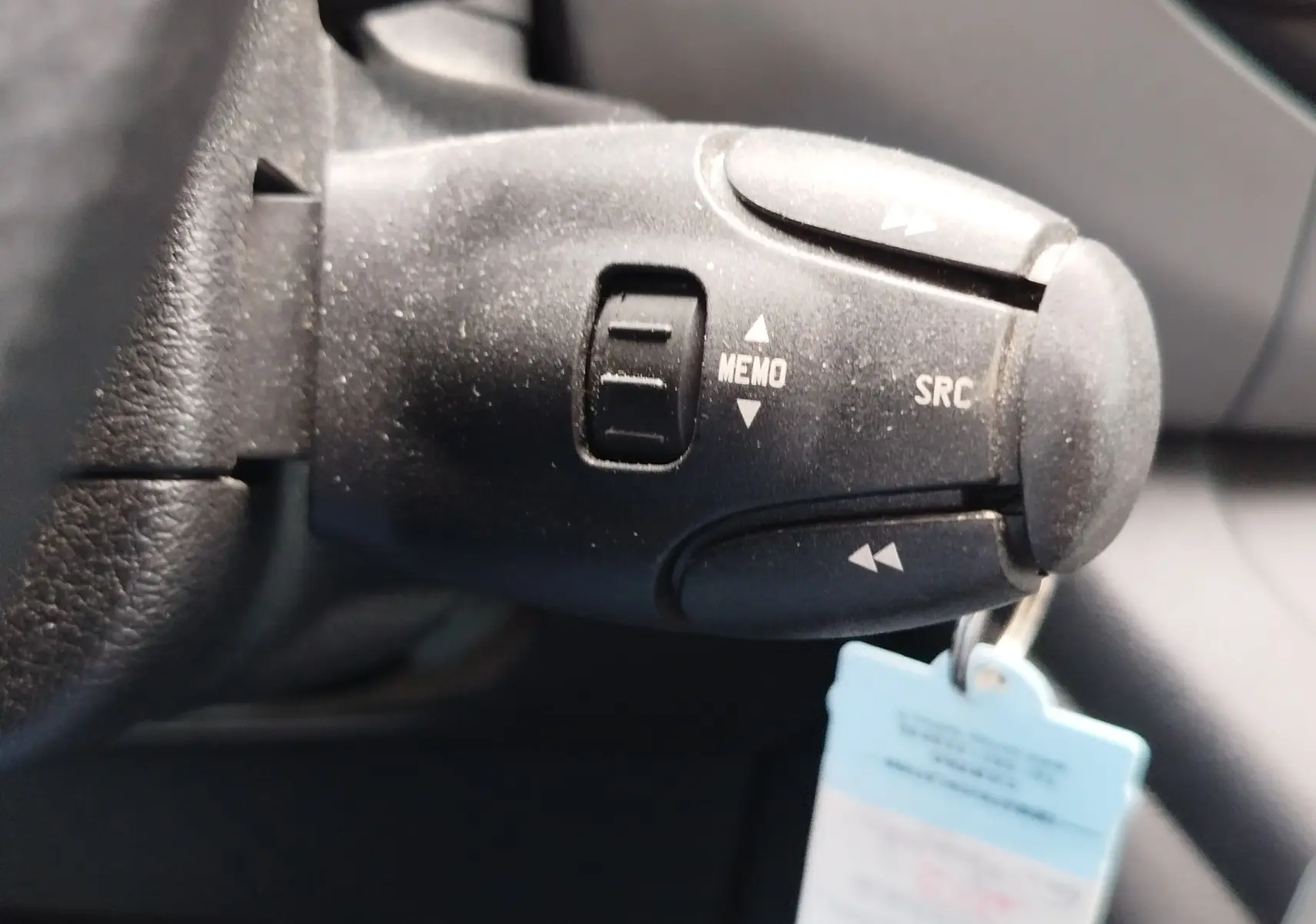 Gros plan sur la commande au volant noire du Peugeot Partner Tepee 2017, montrant les boutons MEMO et SRC.