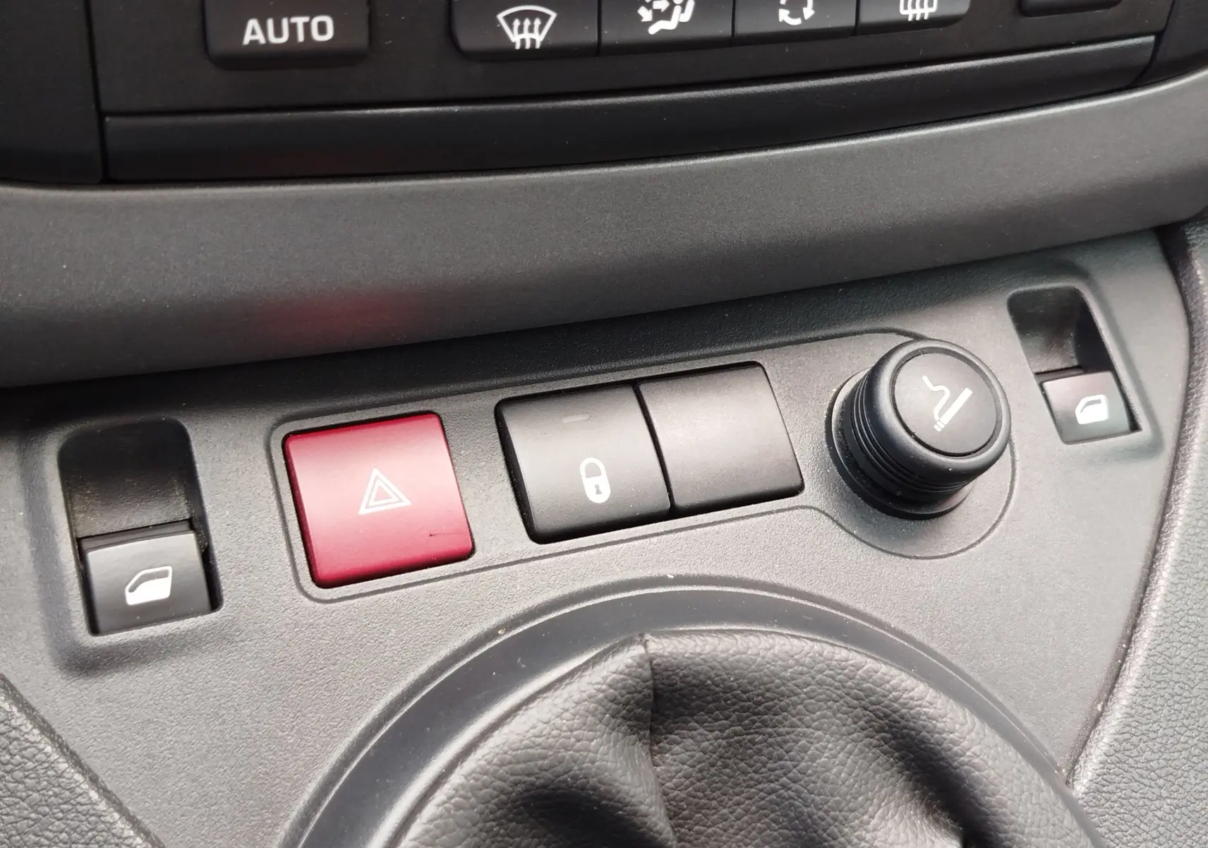 Gros plan sur la console centrale du Peugeot Partner Tepee 2017, montrant les boutons de verrouillage, warning et réglage des rétroviseurs.