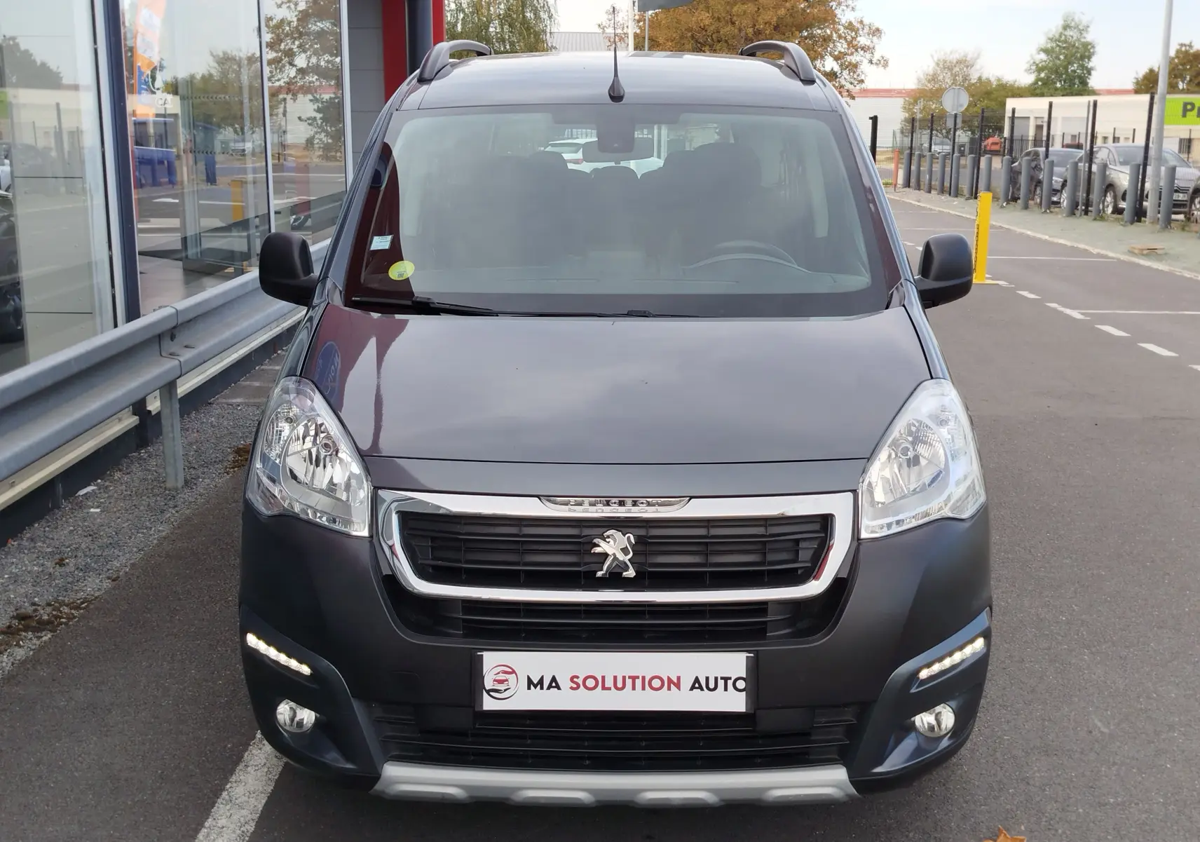 Vue avant d’un Peugeot Partner Tepee gris foncé avec calandre chromée et feux diurnes à LED allumés.