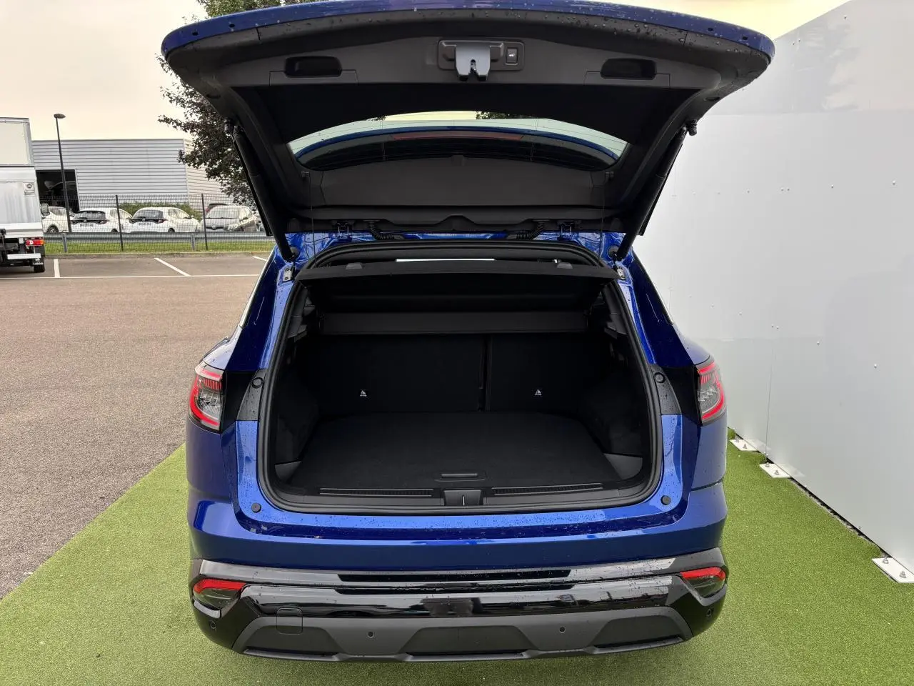 Vue arrière du Renault Austral bleu Iron Metal avec hayon motorisé ouvert dévoilant le coffre spacieux.