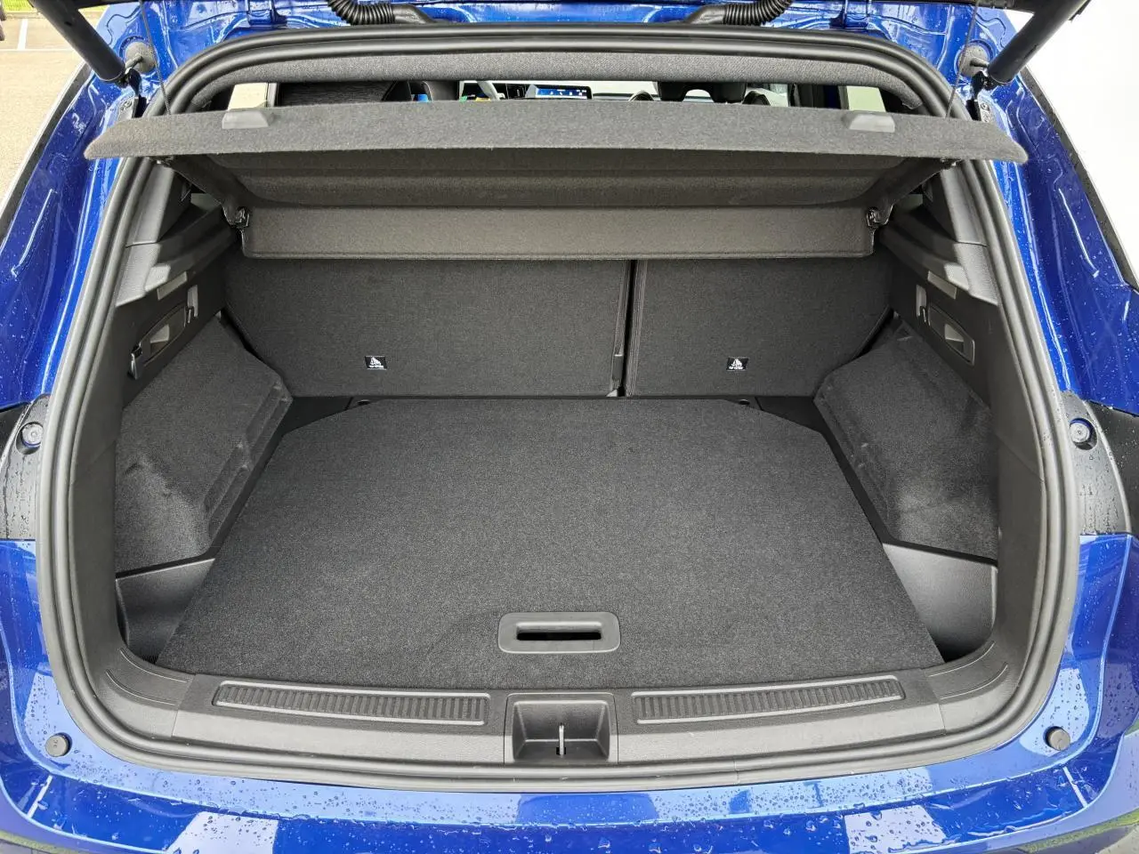 Coffre ouvert vu de l'arrière du Renault Austral bleu Iron Metal, montrant un espace de chargement spacieux et propre.