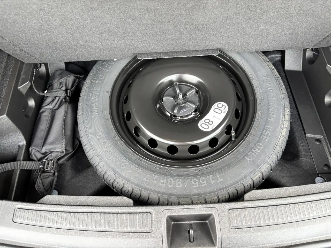 Roue de secours noire en acier dans le coffre du Renault Austral E-Tech Full Hybrid 2025, vue de dessus.