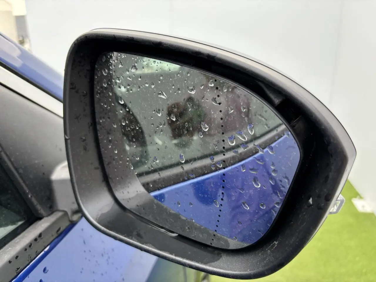 Rétroviseur côté gauche d'un Renault Austral bleu Iron Metal avec gouttes de pluie sur le miroir.