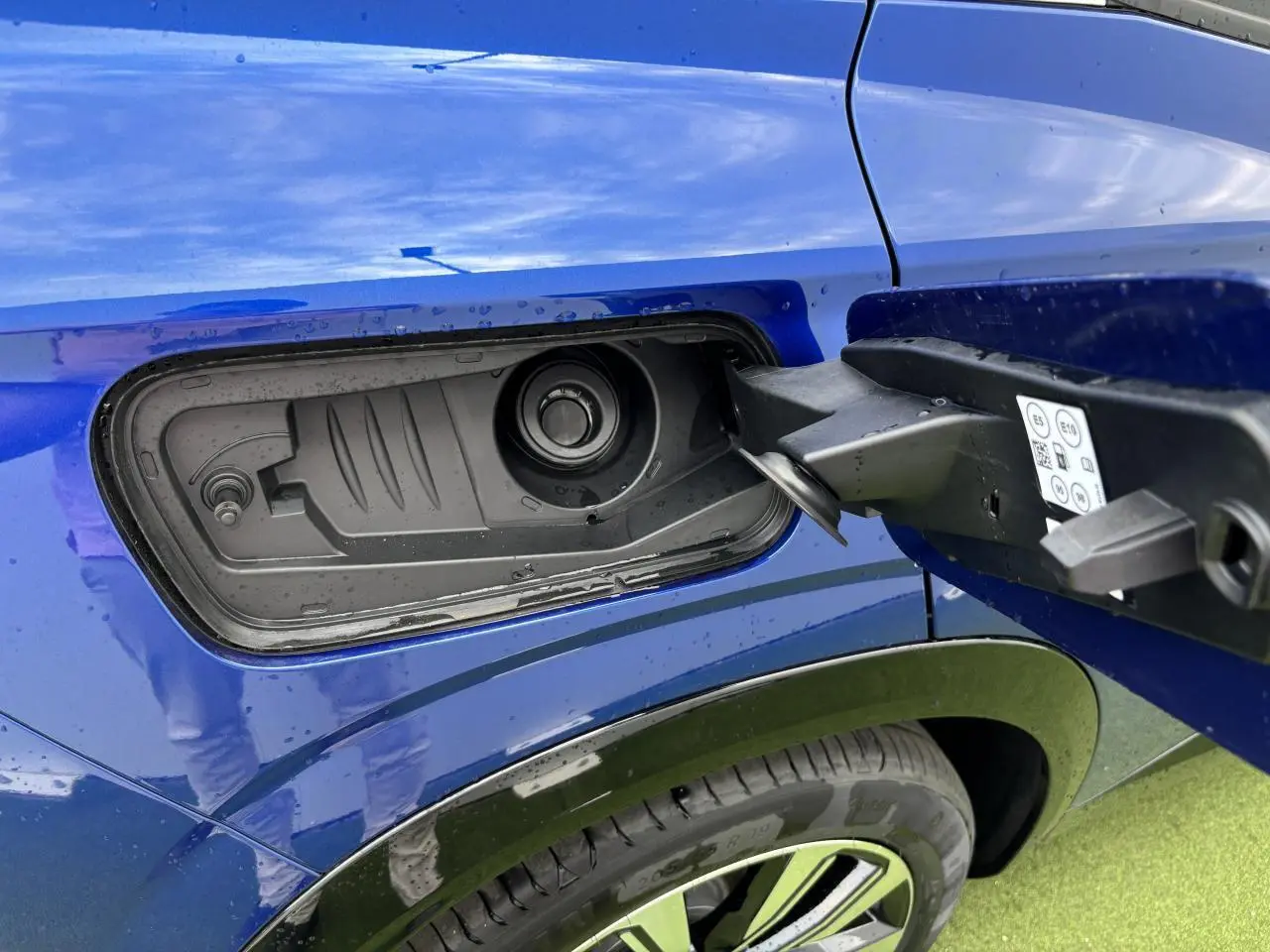 Gros plan sur la trappe de carburant côté gauche du Renault Austral bleu Iron Metal avec jante alliage 19 pouces visible.