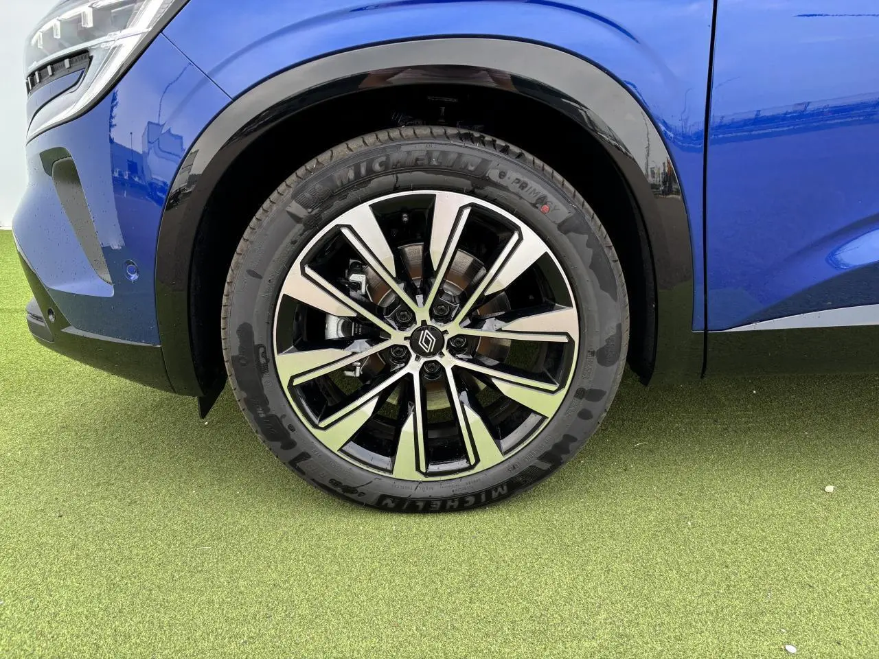 Gros plan sur la jante alliage noire et diamantée 19 pouces du côté avant gauche du Renault Austral bleu Iron Metal.