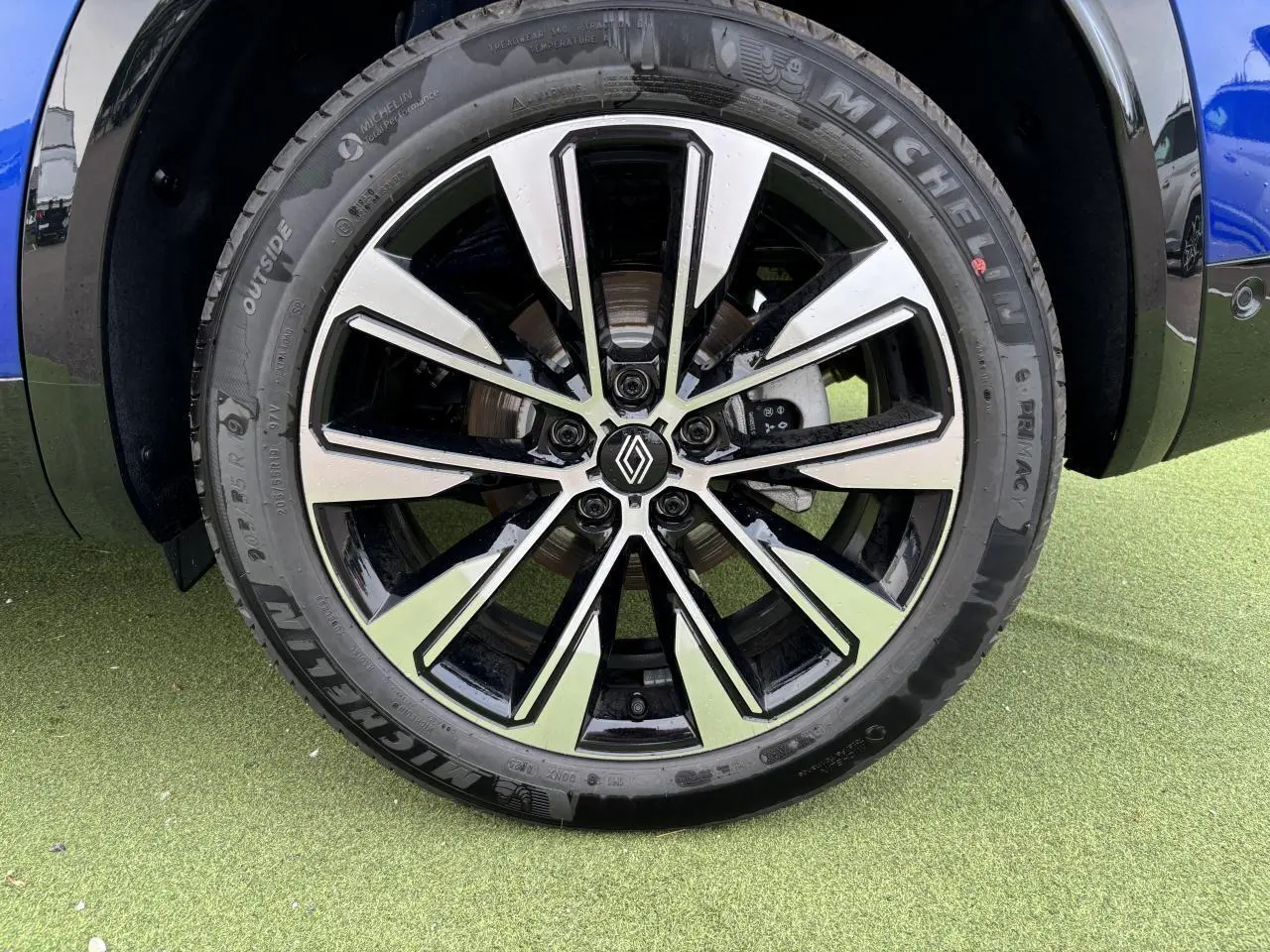 Gros plan sur la jante alliage noire et argentée du Renault Austral bleu Iron Metal, avec logo Renault au centre.