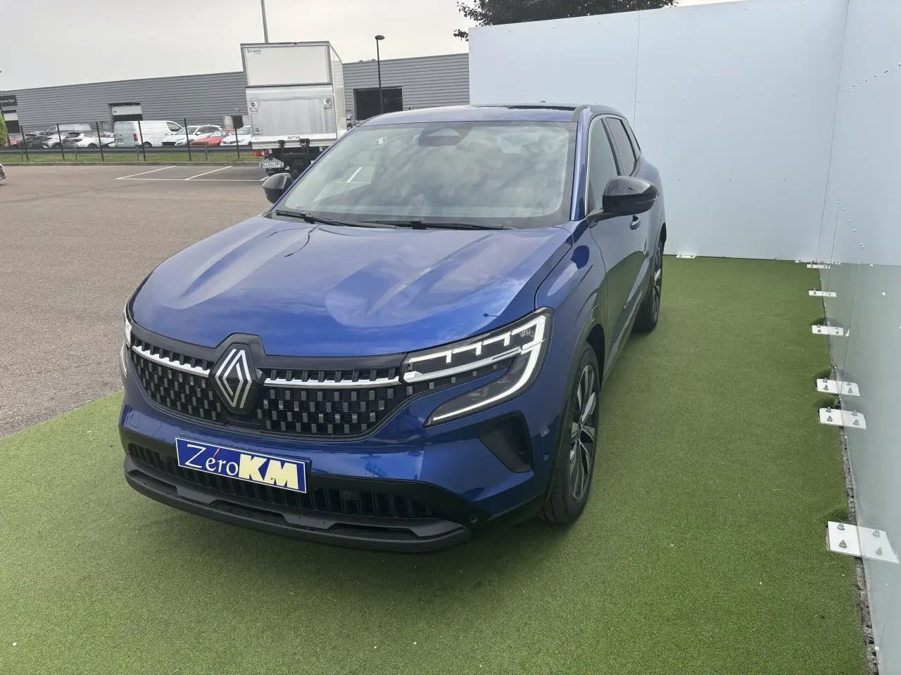 Renault Austral bleu Iron Metal en 3/4 avant droit, avec calandre damier ice black et jantes alliage noires.
