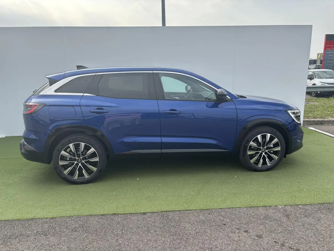 Profil côté droit du Renault Austral bleu Iron Metal 2025 avec jantes alliage noires diamantées et vitres arrière surteintées.