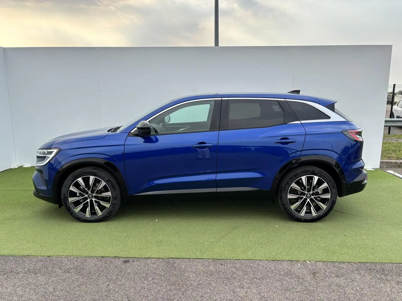 Profil droit du Renault Austral 2025 bleu Iron Metal avec jantes alliage 19 pouces et toit noir étoilé.