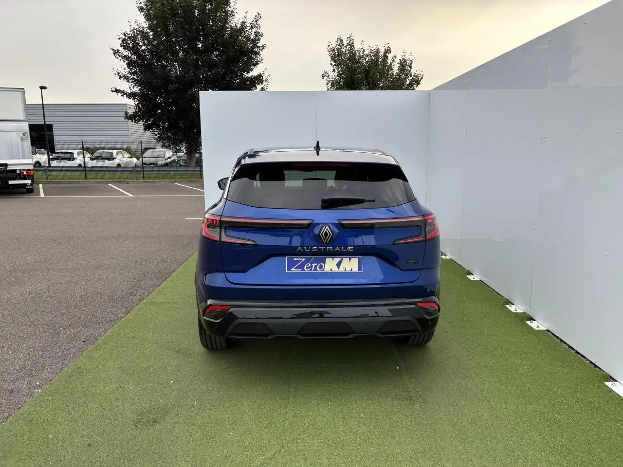 Vue arrière du Renault Austral bleu Iron Metal avec hayon motorisé et feux LED adaptatifs sur fond urbain.