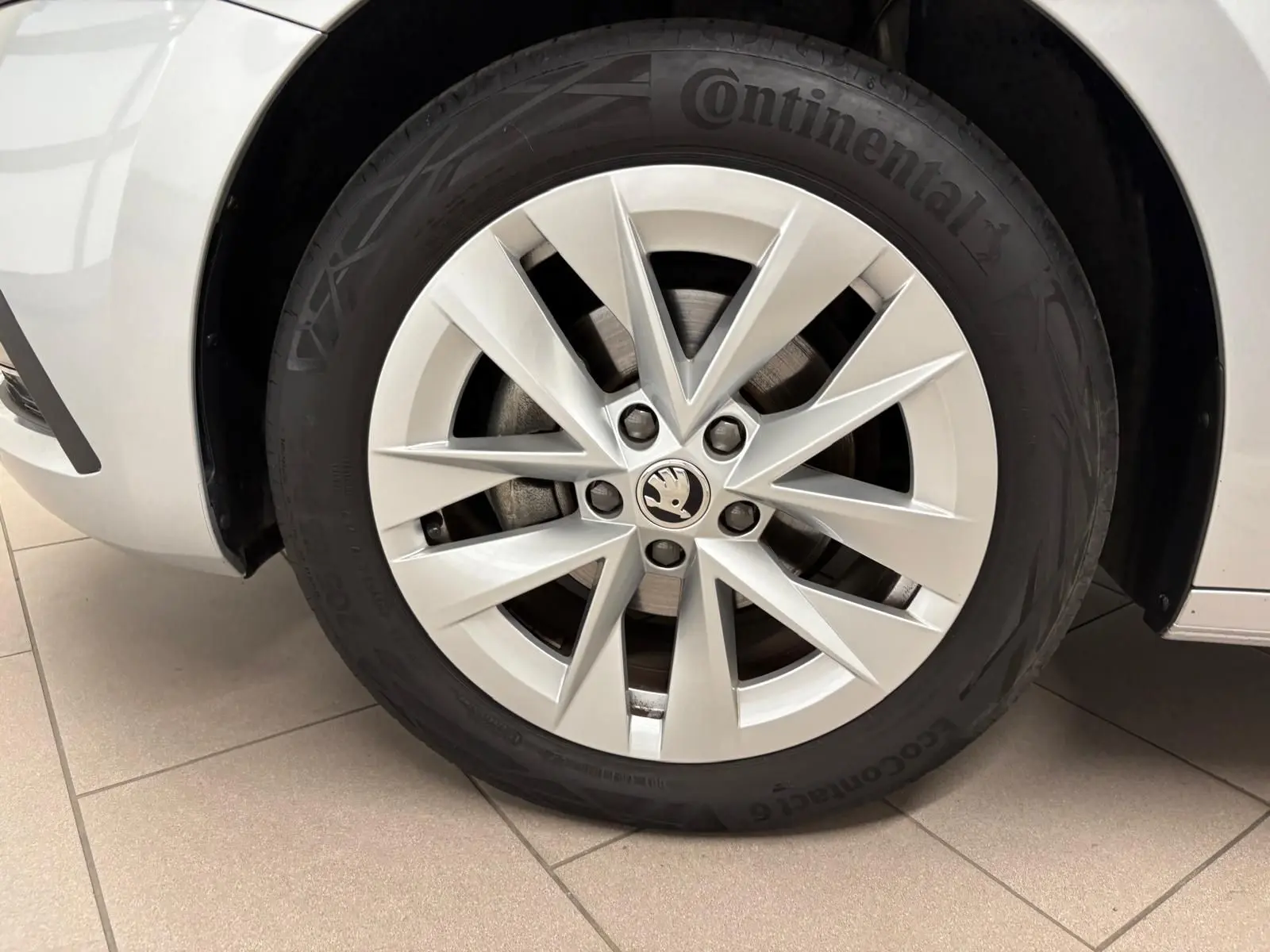 Gros plan sur la roue avant gauche d'une Skoda Octavia Combi gris argent 2023, avec jante alliage et pneu Continental.