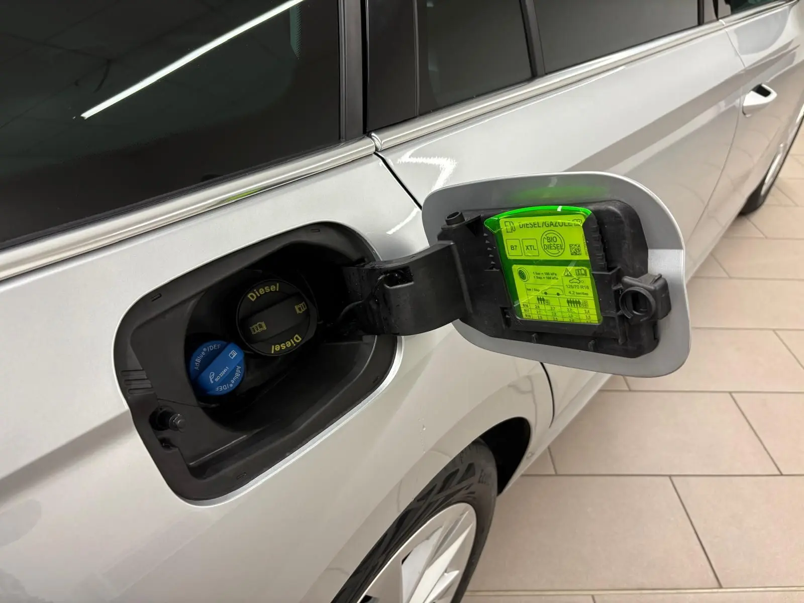 Bouchon de réservoir diesel ouvert côté gauche d'une Skoda Octavia Combi gris argent 2023 avec consignes sur la trappe.