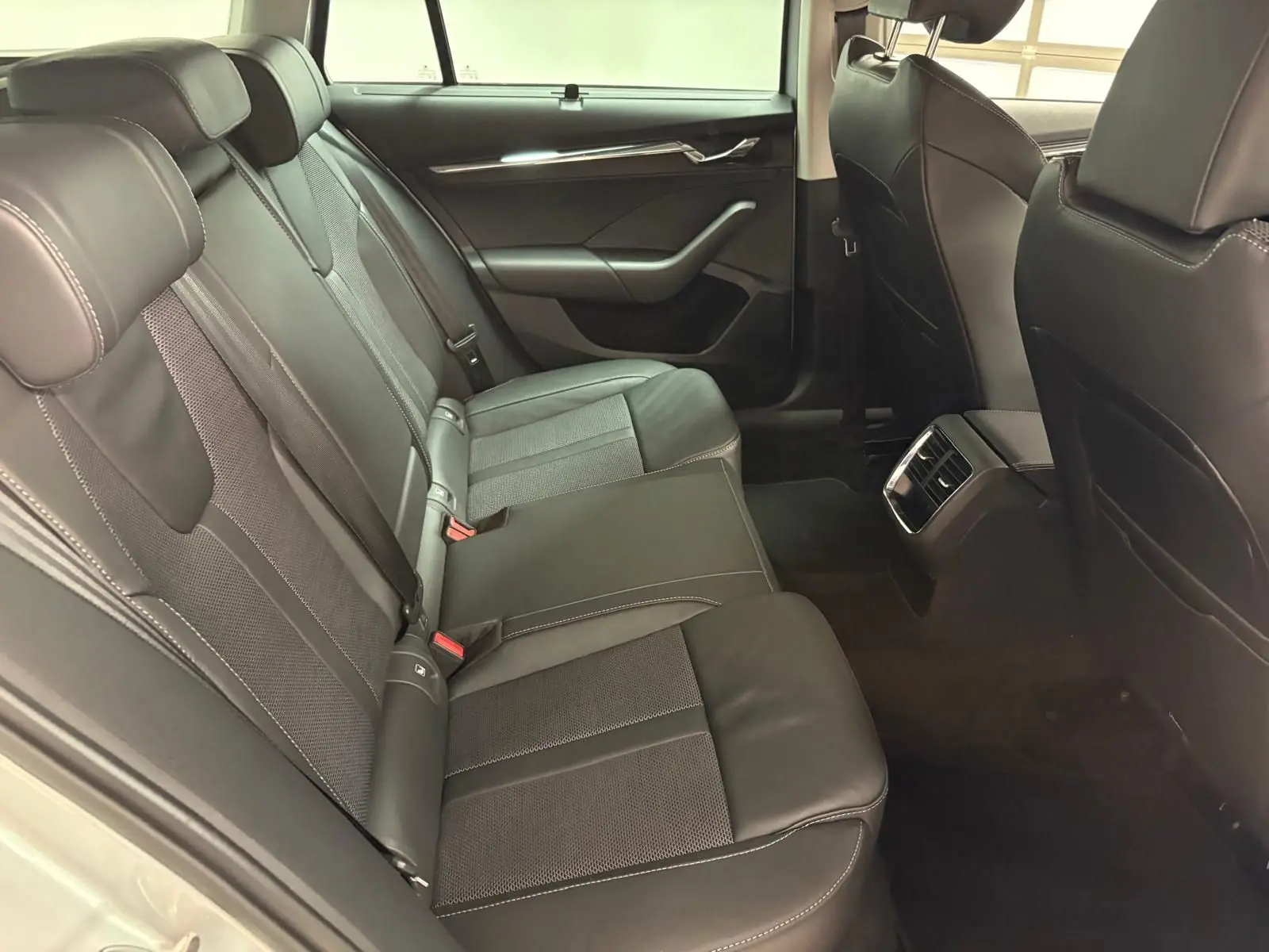 Vue intérieure arrière droite des sièges en cuir noir de la Skoda Octavia Combi gris argent 2023, version Style.