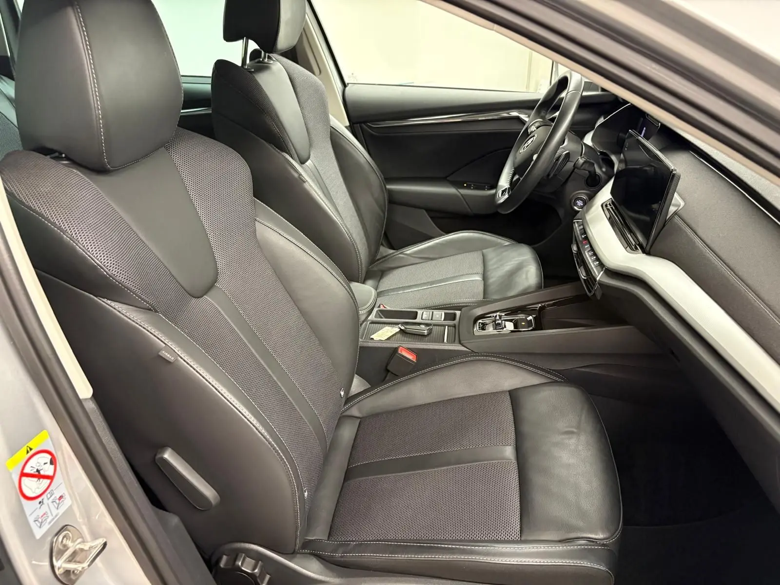 Intérieur avant droit de la Skoda Octavia Combi gris argent 2023, sièges cuir et tissu avec console centrale moderne.
