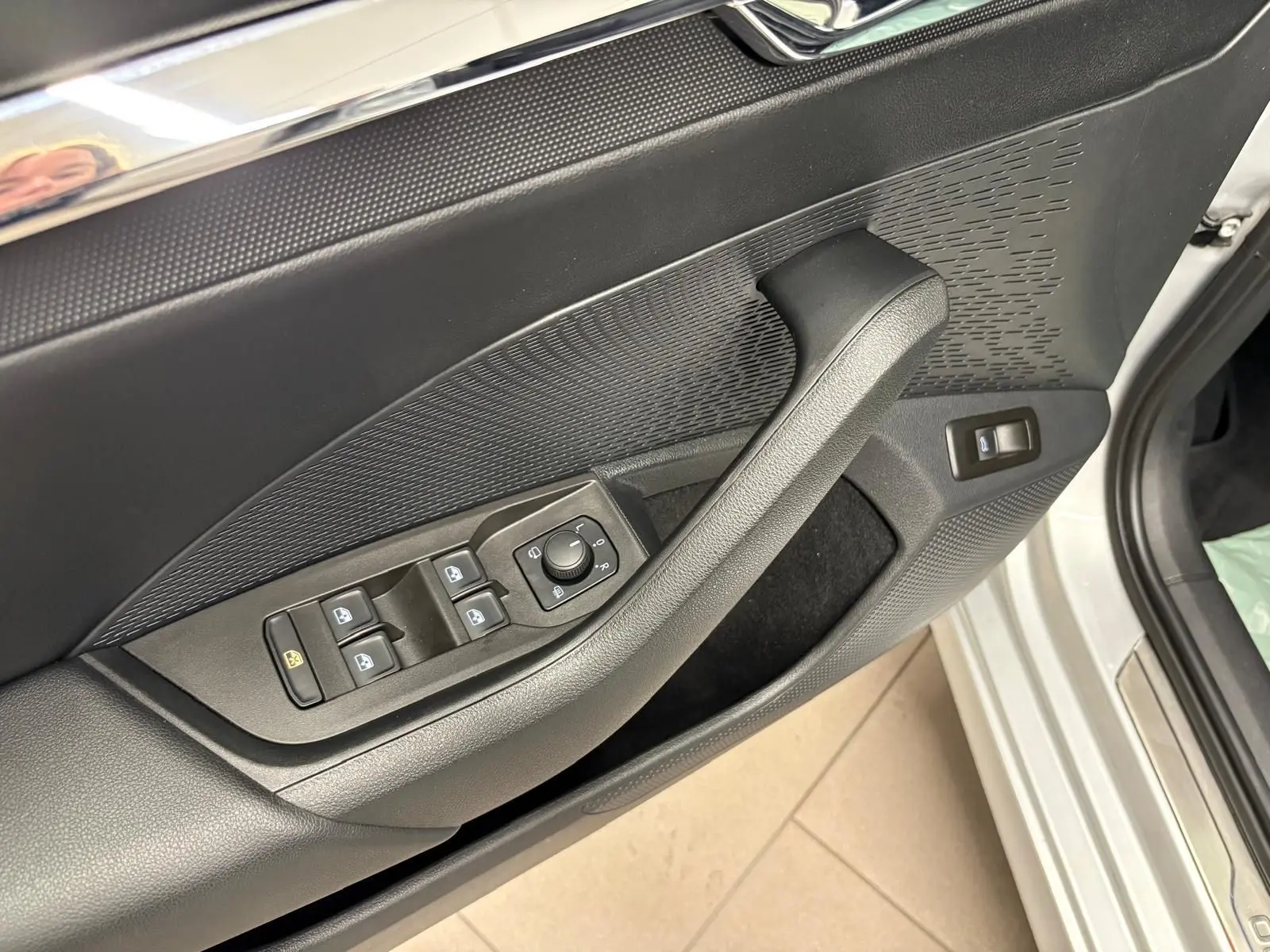Gros plan sur la porte côté conducteur de la Skoda Octavia Combi gris argent 2023, avec commandes des vitres et rétroviseurs.