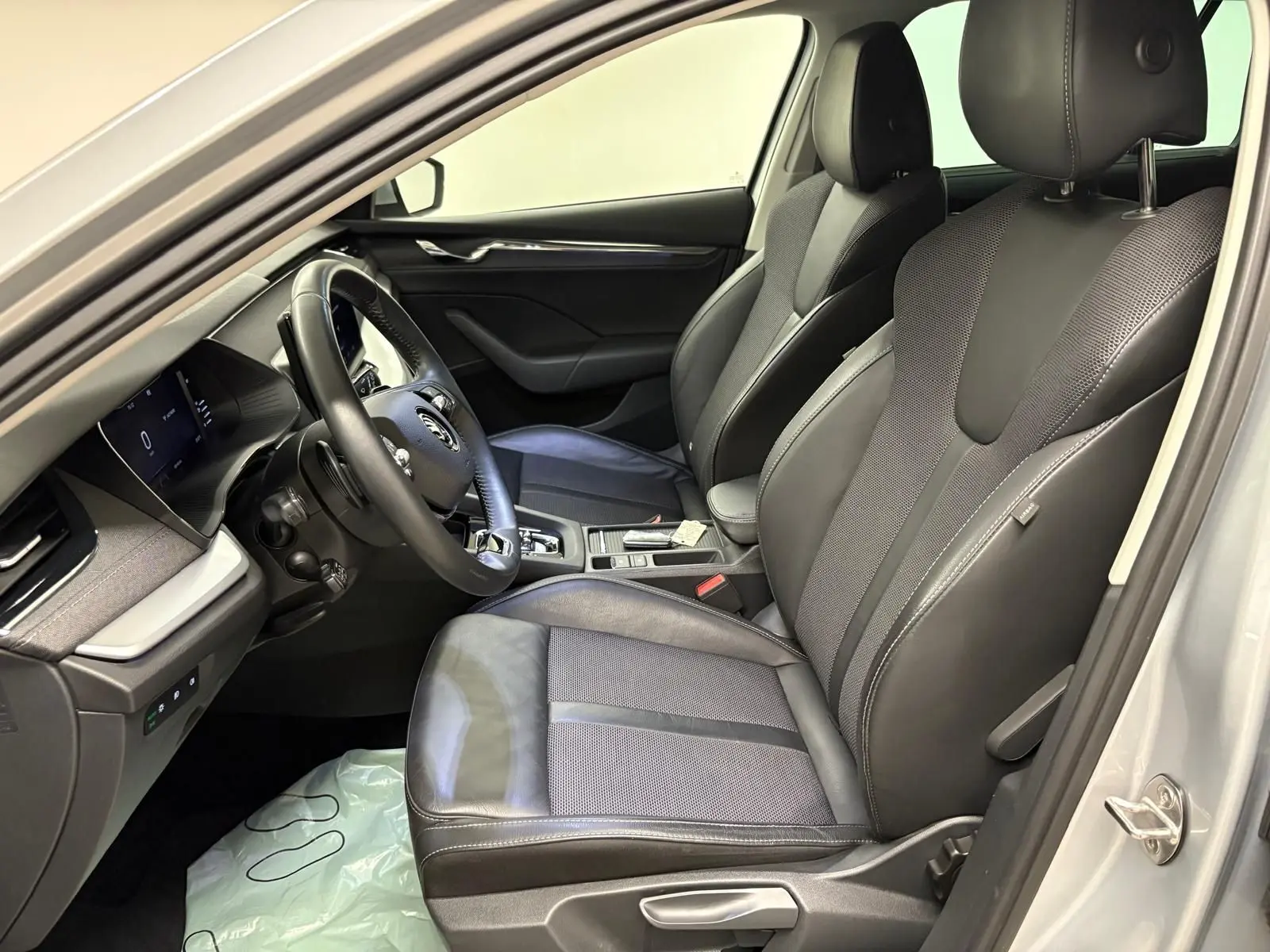 Intérieur côté conducteur de la Skoda Octavia Combi gris argent 2023, sièges cuir et tableau de bord moderne visibles.