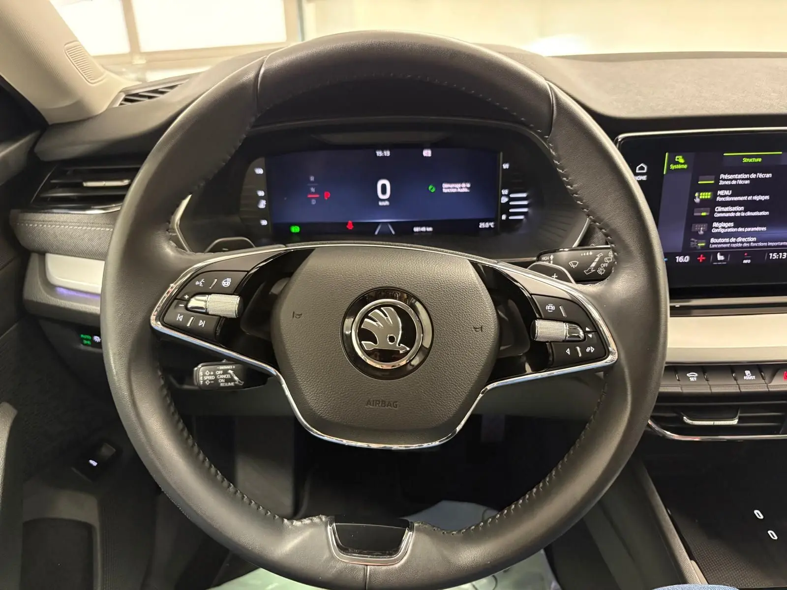 Vue intérieure centrée sur le volant cuir noir d'une Skoda Octavia Combi 2023, avec tableau de bord numérique et écran tactile.