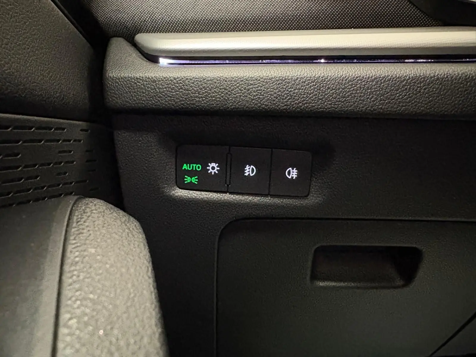 Détail des commandes d'éclairage avec mode automatique sur le tableau de bord d'une Skoda Octavia Combi gris argent 2023.