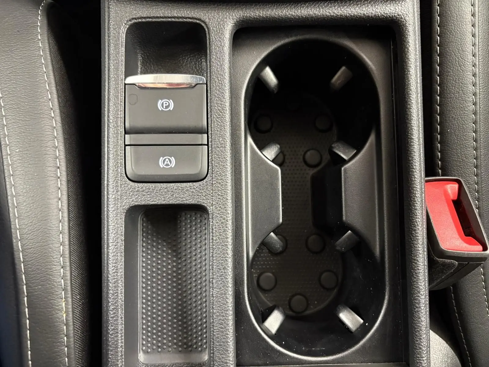 Gros plan sur la console centrale de la Skoda Octavia Combi gris argent, montrant les porte-gobelets et commandes électroniques.