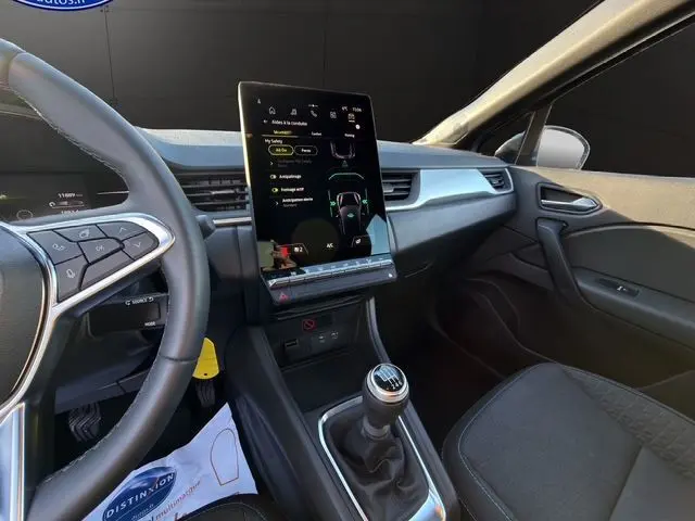 Vue intérieure du tableau de bord et console centrale du Renault Captur 2024 avec écran tactile vertical et boîte manuelle.