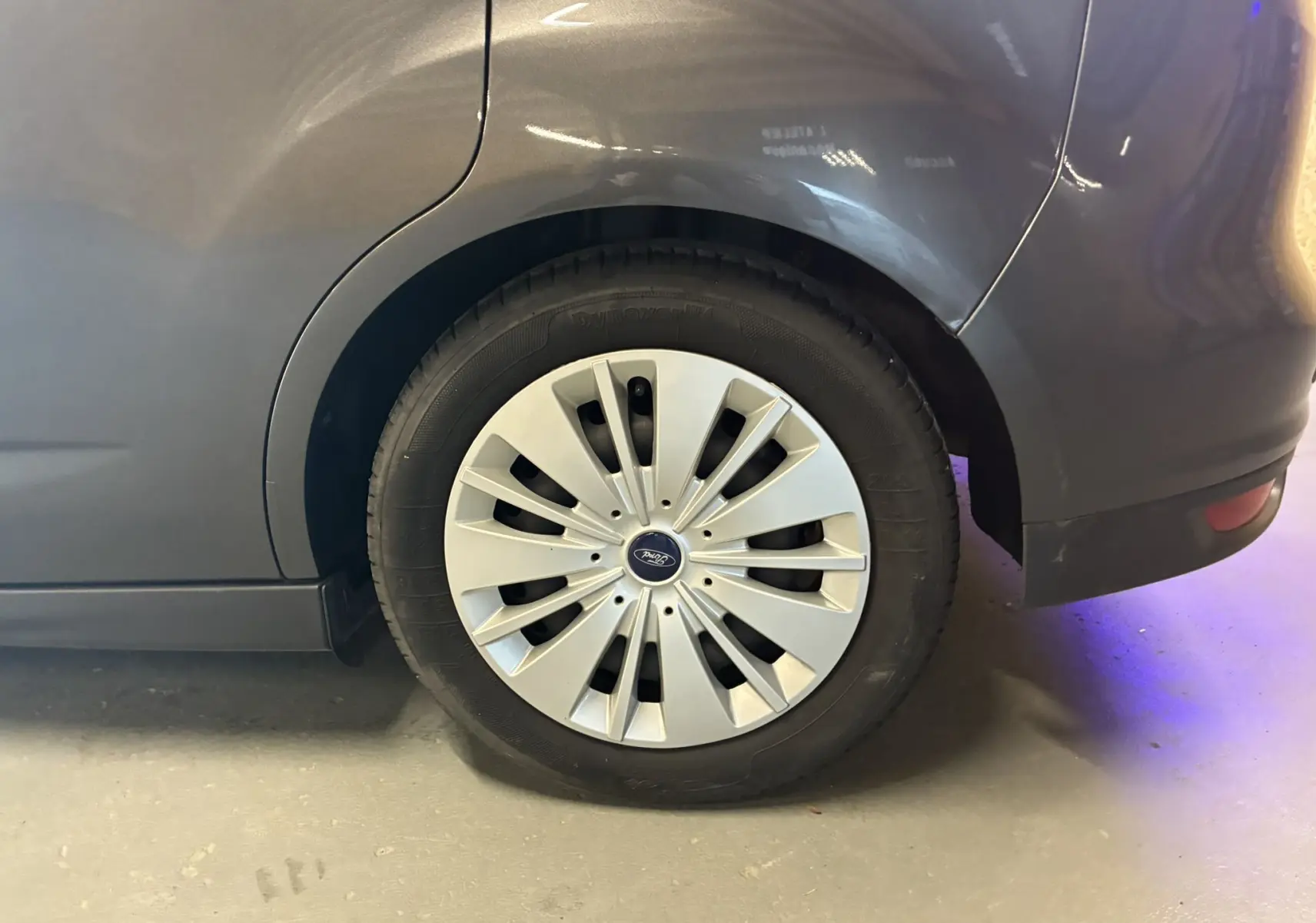 Gros plan sur la roue arrière droite grise d'une Ford C-MAX 1.5 TDCI 120 Trend Business avec enjoliveur argenté.