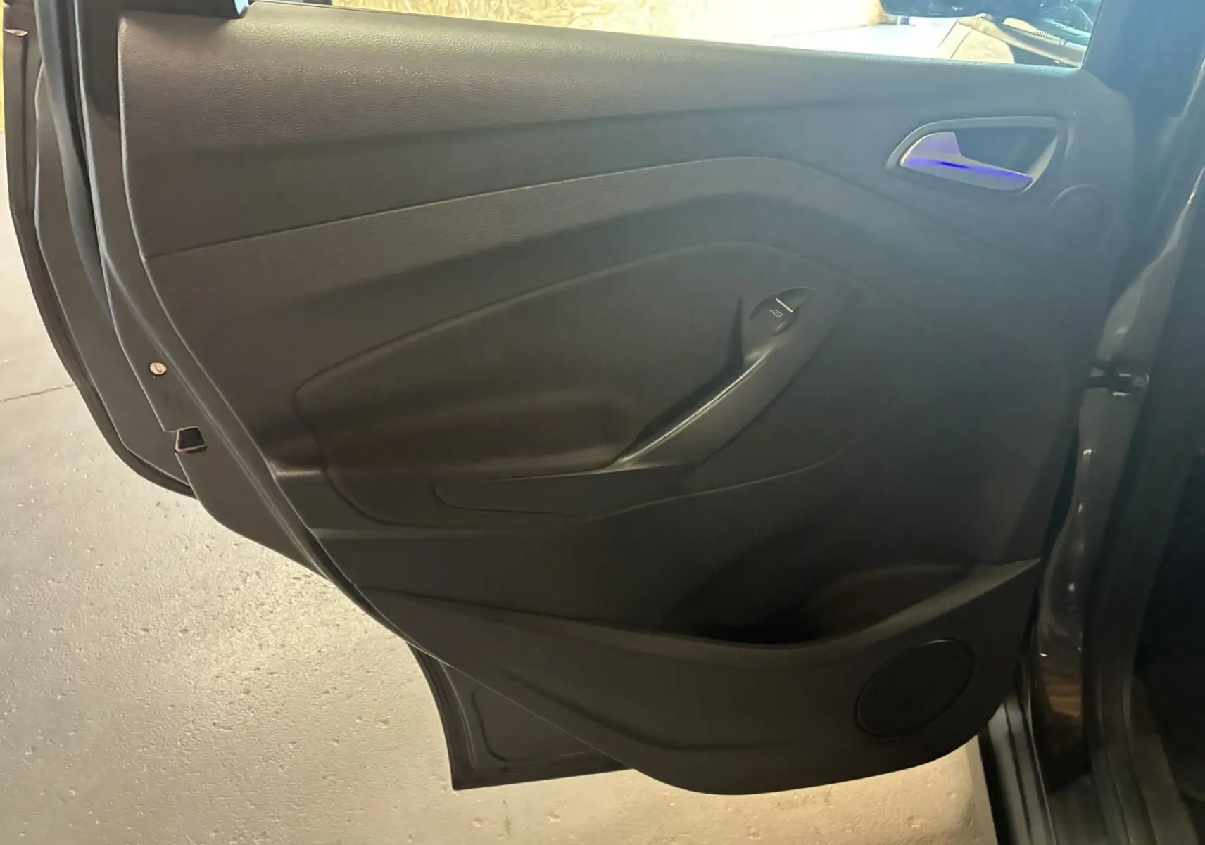 Gros plan sur la porte arrière droite intérieure noire du Ford C-MAX gris 2015 avec poignée et commande de vitre.