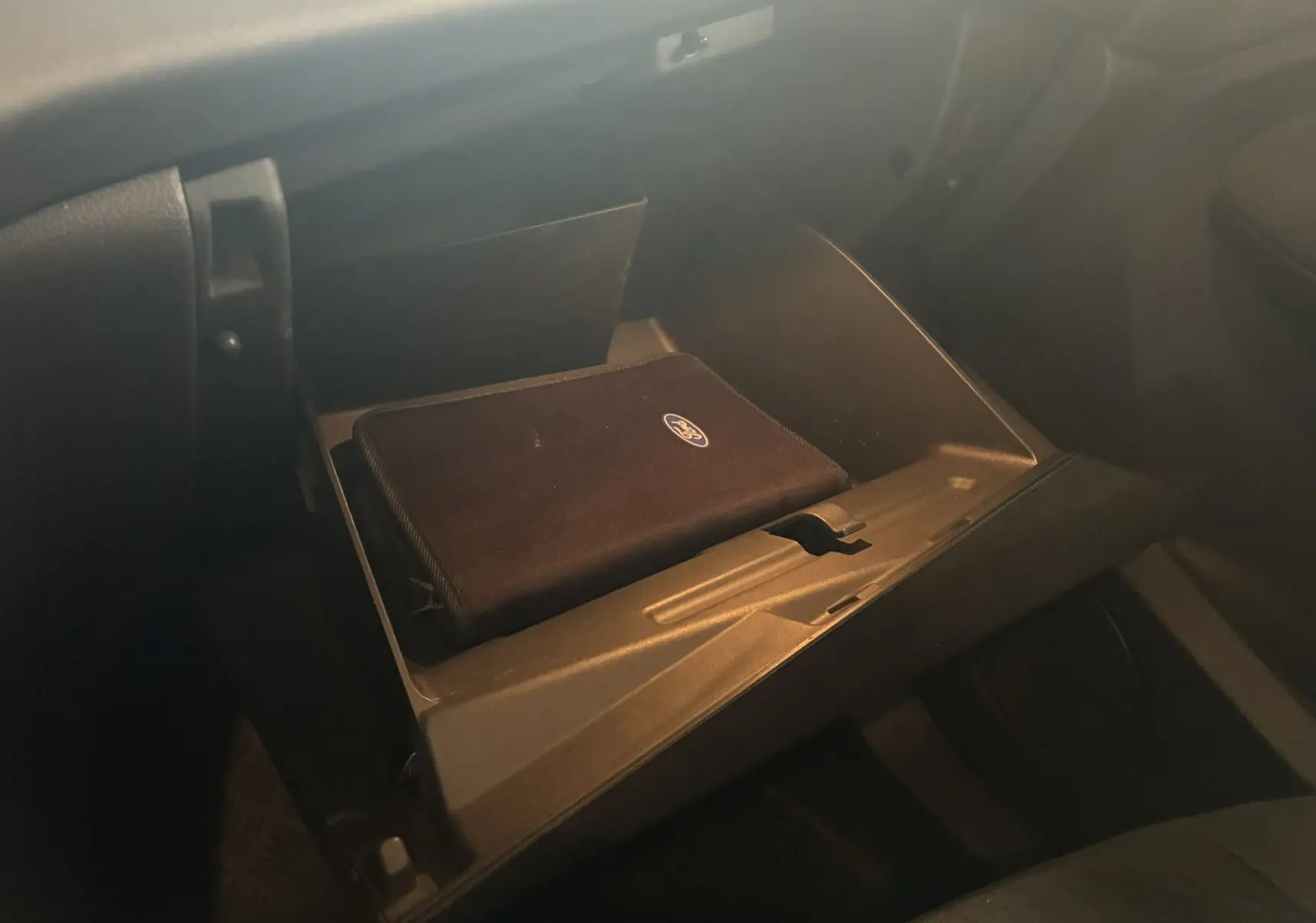 Boîte à gants ouverte côté passager avec pochette Ford noire à l'intérieur d'un Ford C-MAX gris 2015.