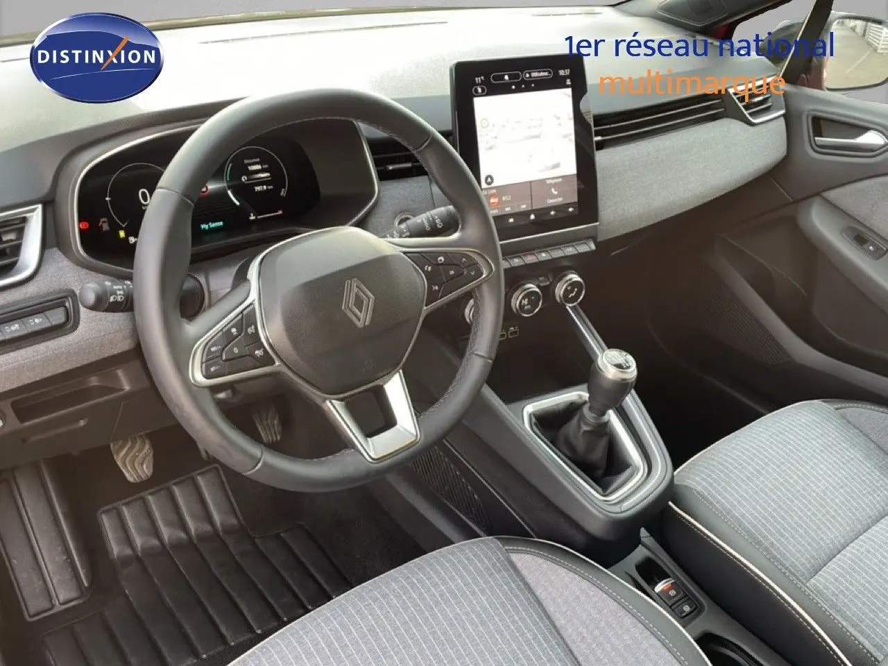 Intérieur de la Renault Clio 2025 vu côté conducteur, volant cuir, tableau de bord numérique et levier de vitesse manuel.
