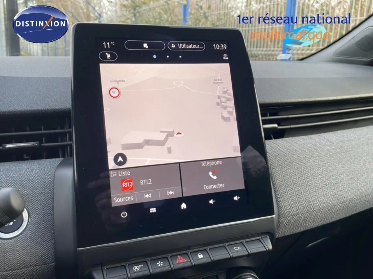 Vue rapprochée de l’écran tactile central de la Renault Clio rouge Désir Métal 2025, affichant la navigation et les commandes multimédia.