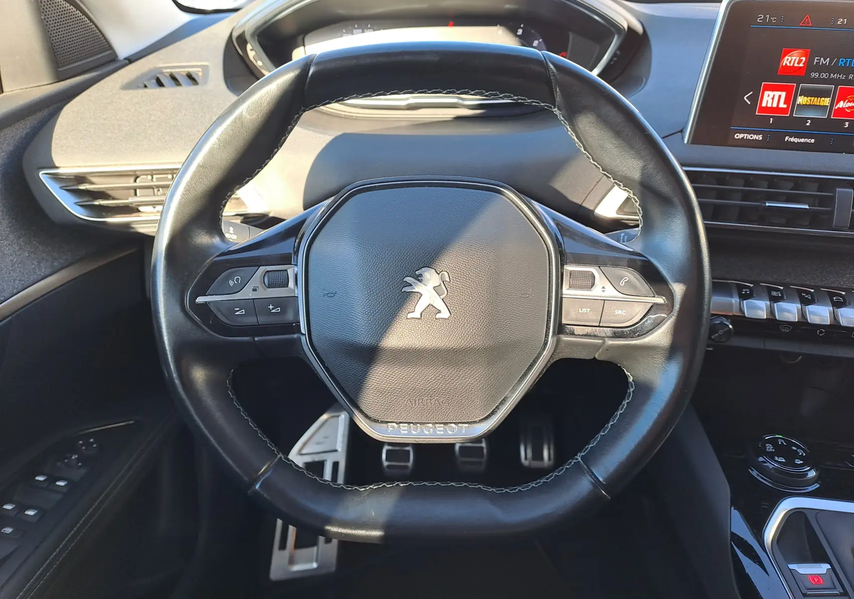 Vue rapprochée du volant cuir noir du Peugeot 5008 2019 avec commandes intégrées et tableau de bord numérique.