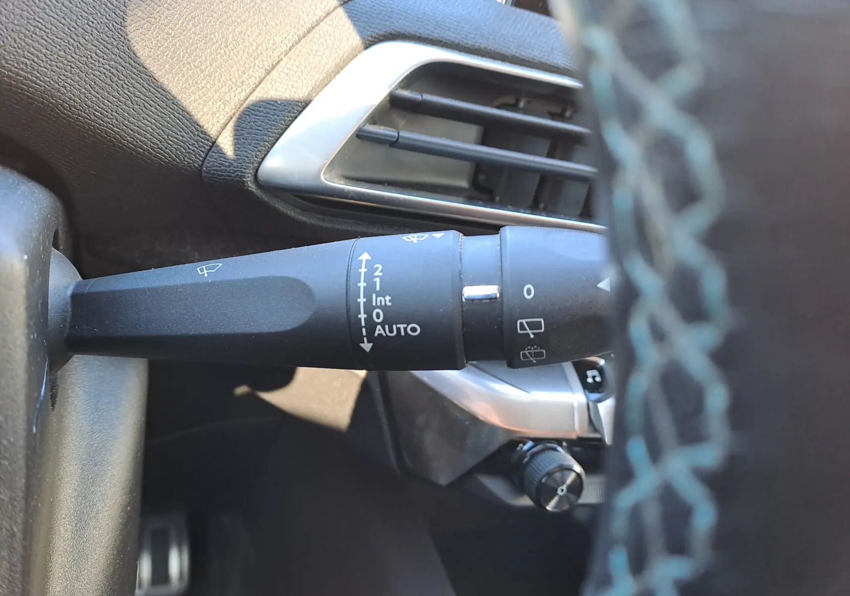 Gros plan sur la commande d'essuie-glace à gauche du volant dans l'habitacle du Peugeot 5008 gris 2019.