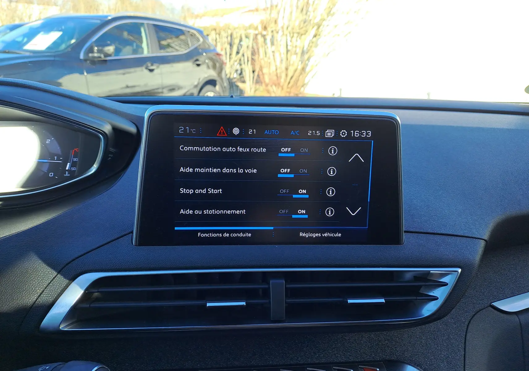 Écran tactile central du tableau de bord du Peugeot 5008 gris, affichant les réglages d'aides à la conduite.