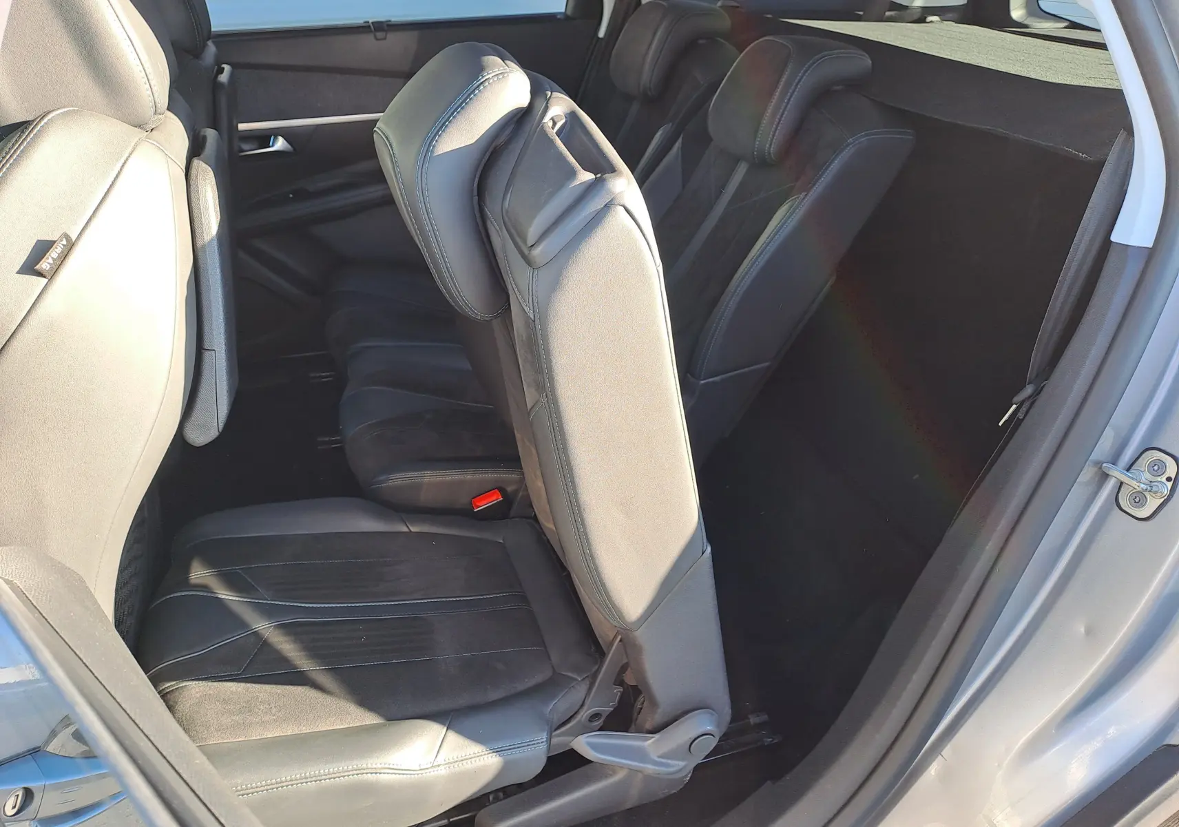Vue intérieure côté droit du Peugeot 5008 gris 2019, montrant la banquette arrière rabattue et les sièges en cuir noir.