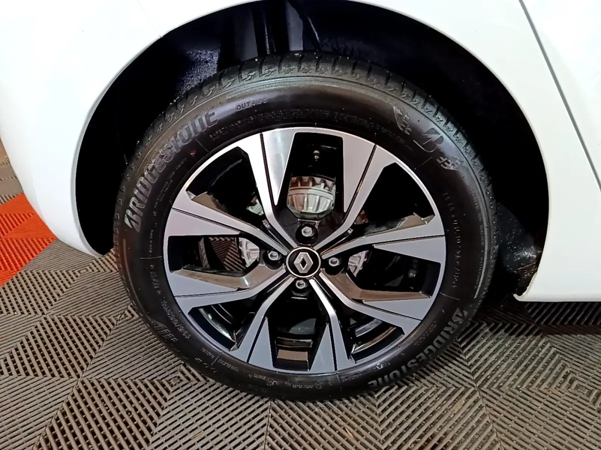 Gros plan sur la roue avant droite blanche d'une Renault Clio 2023 avec jante alliage noire et argentée.
