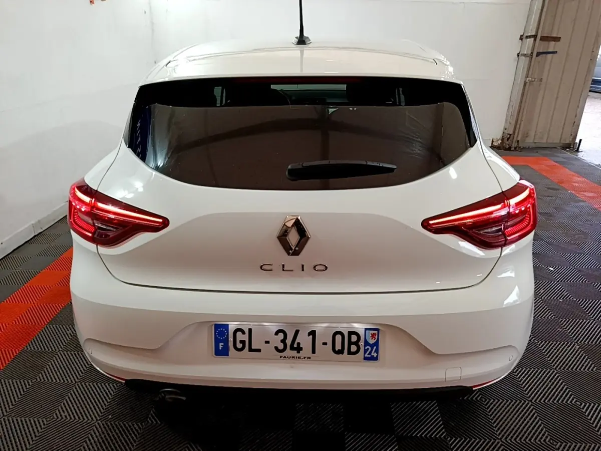 Vue arrière d'une Renault Clio blanche 2023 avec feux LED allumés dans un garage fermé.