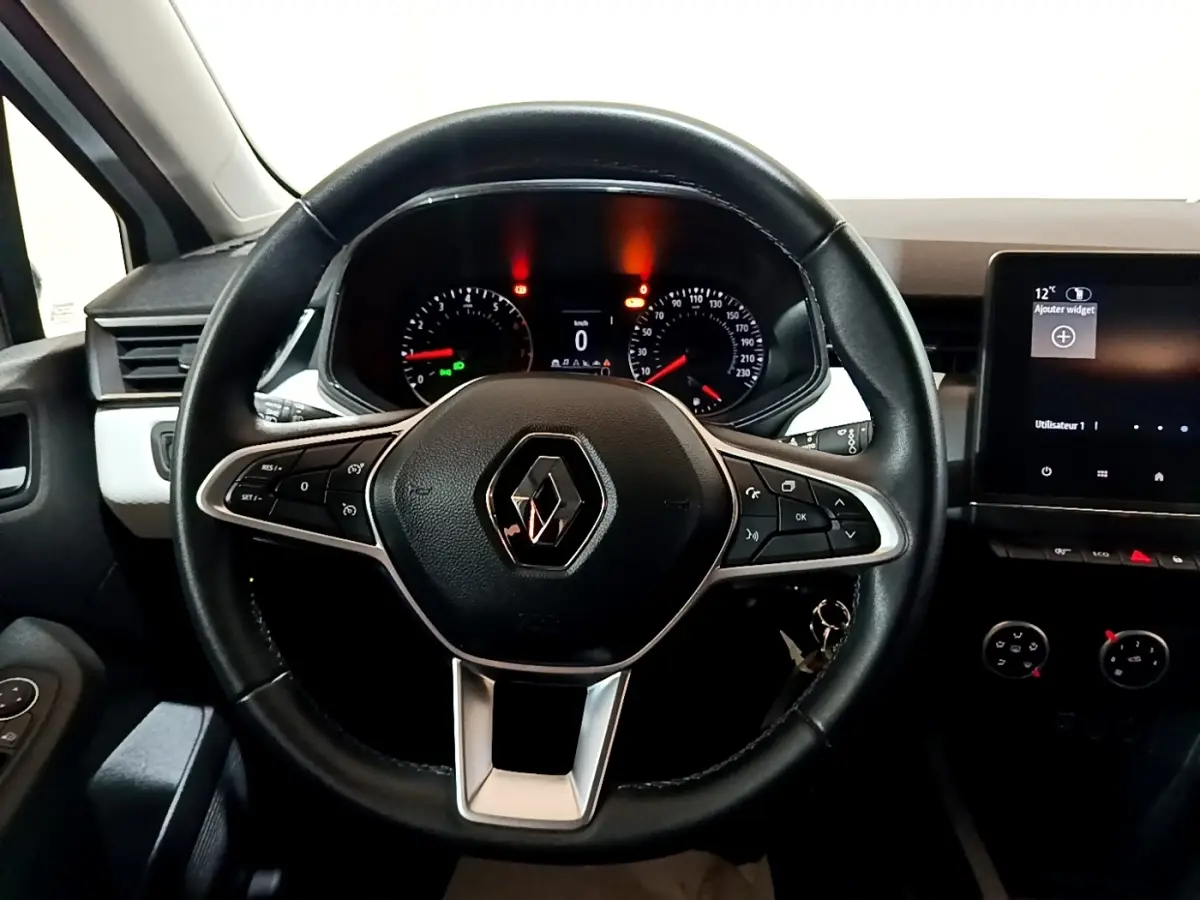 Vue intérieure centrée sur le volant noir de la Renault Clio 2023 avec tableau de bord et écran tactile visible à droite.