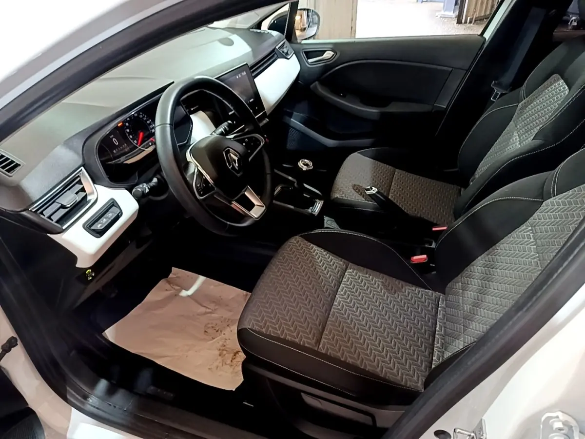 Vue intérieure côté conducteur de la Renault Clio Business TCe 100 GPL 2023 avec sièges tissu gris et tableau de bord noir et blanc.