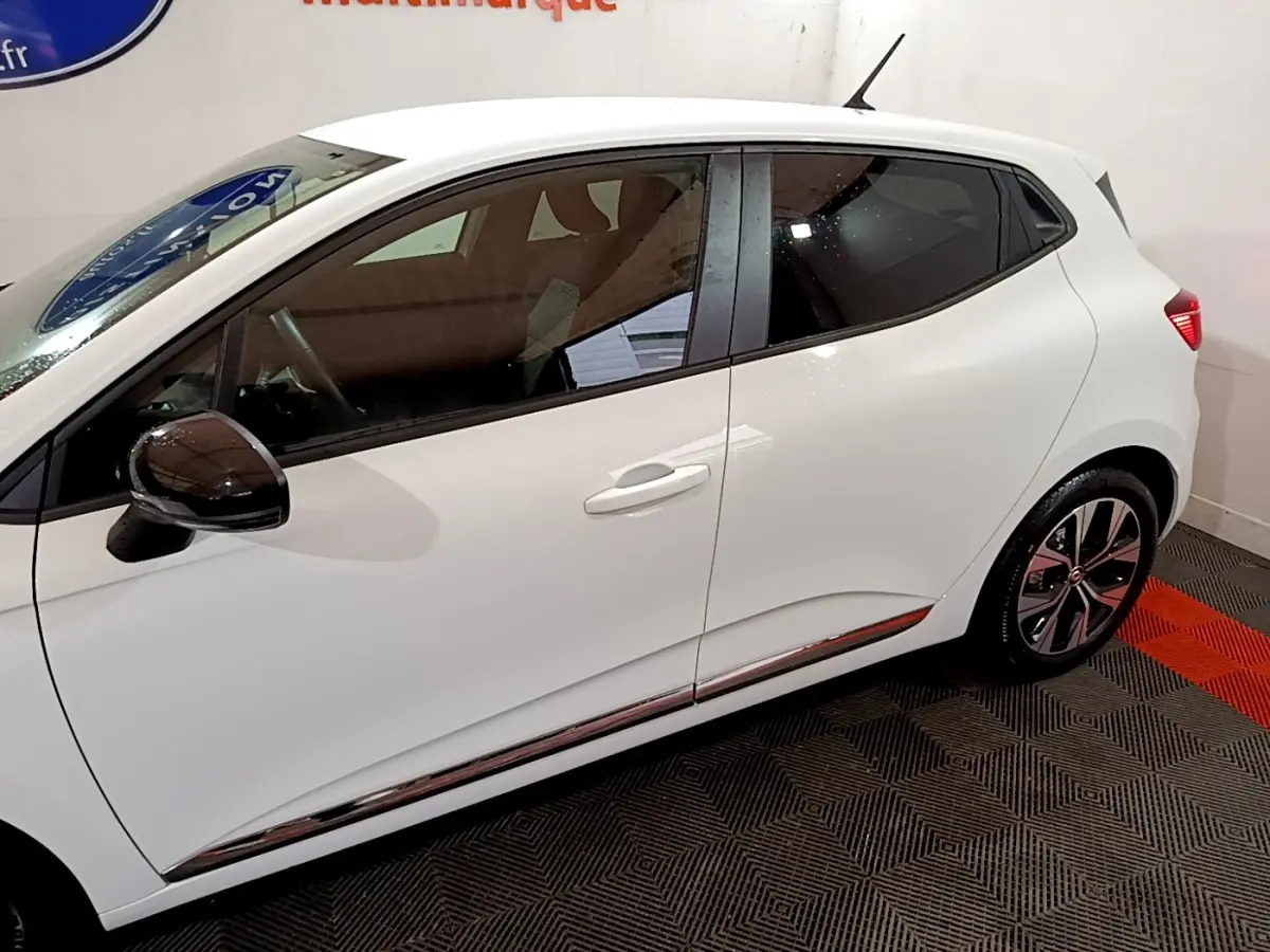 Profil droit d'une Renault Clio blanche 2023 avec rétroviseurs noirs et jantes alliage distinctives.
