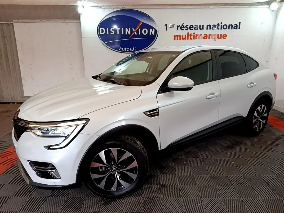 Renault Arkana blanc en 3/4 avant droit, SUV hybride avec jantes noires et phares LED allumés.