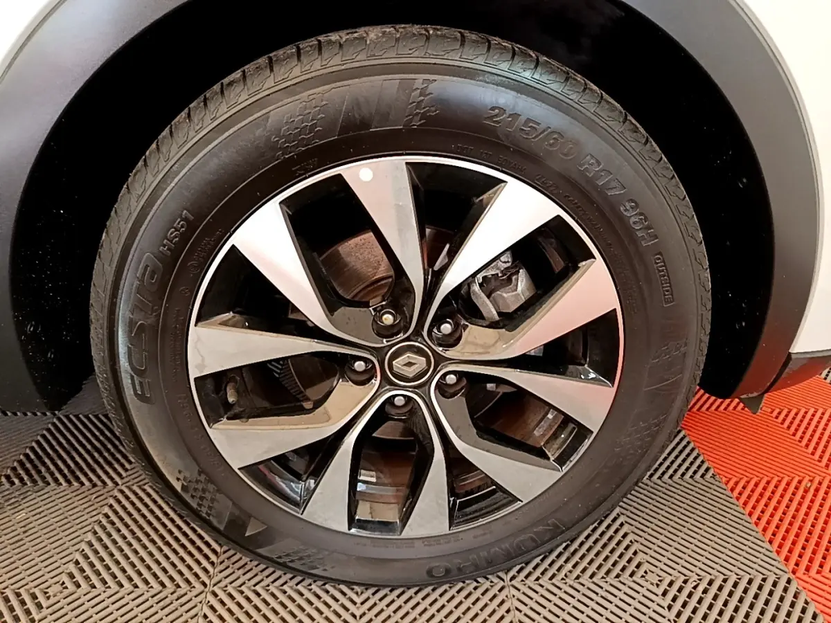 Gros plan sur la roue avant droite du Renault Arkana blanc, mettant en valeur la jante alliage bicolore et le logo central.