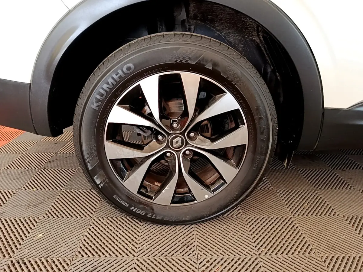 Gros plan sur la roue avant droite d’un Renault Arkana blanc, avec jante alliage bicolore et pneu Kumho.