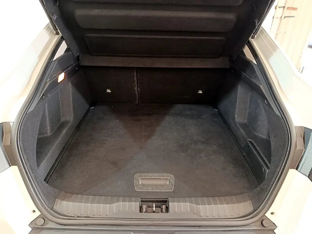 Coffre ouvert vu de l'arrière d'un Renault Arkana blanc, montrant un espace de chargement propre et spacieux.