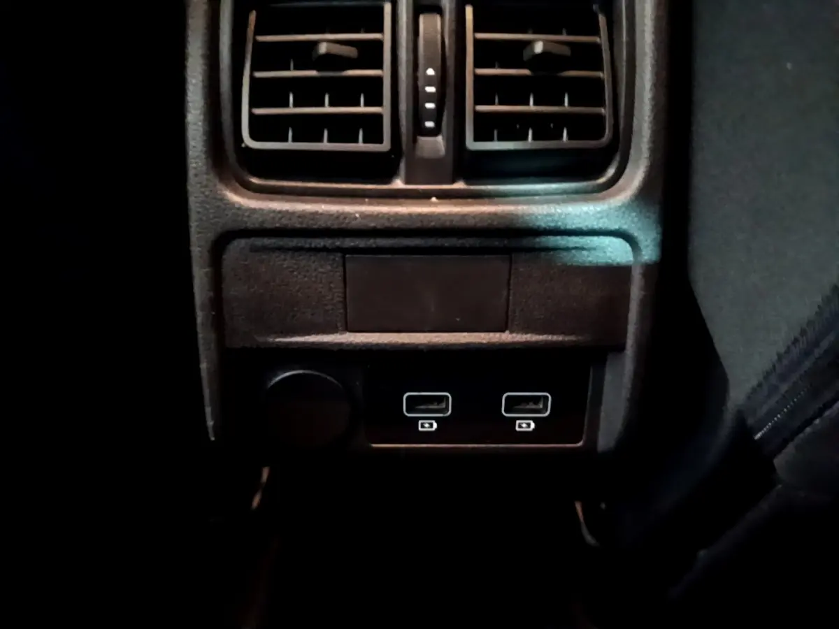 Gros plan sur la console arrière noire du Renault Arkana Evolution E-Tech avec prises USB et aérateurs visibles.