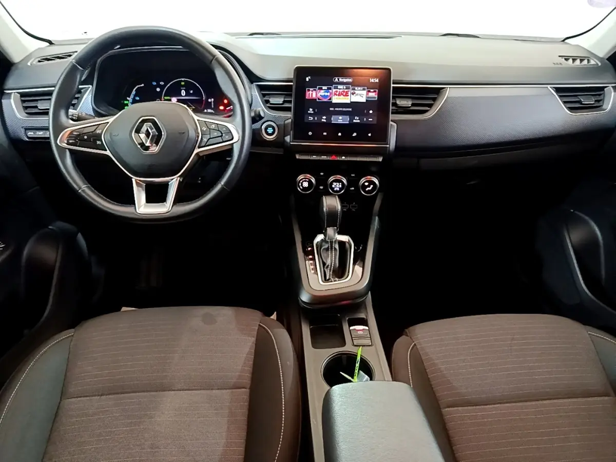 Vue intérieure avant du tableau de bord et console centrale du Renault Arkana blanc avec écran tactile vertical et volant multifonctions.