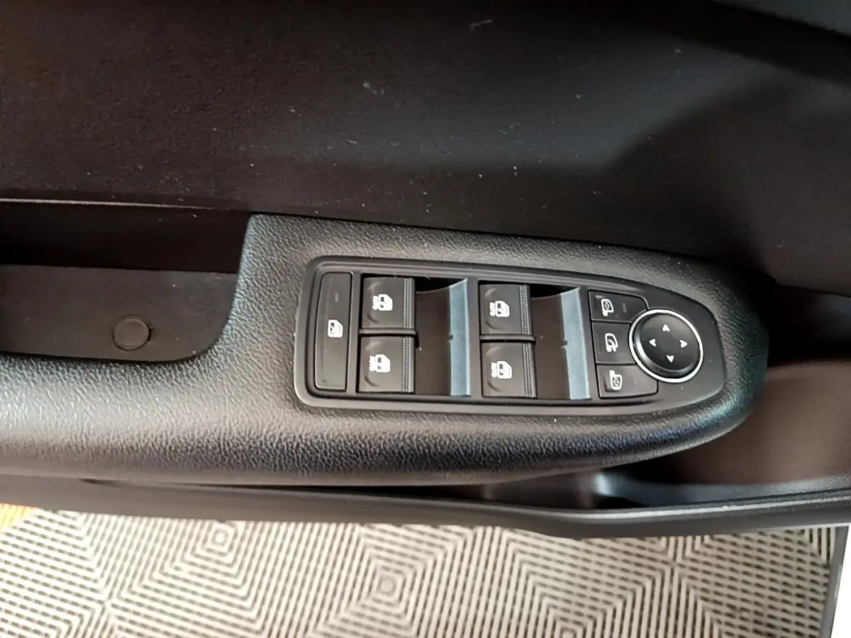 Vue rapprochée des commandes de lève-vitres et rétroviseurs sur la porte côté conducteur d’une Renault Arkana blanc.