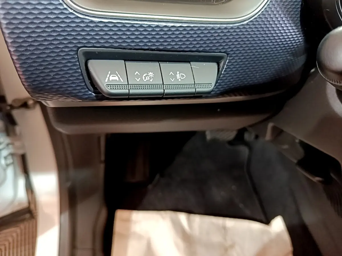 Détail des commandes d'assistance à la conduite sur tableau de bord bleu foncé intérieur Renault Arkana blanc.