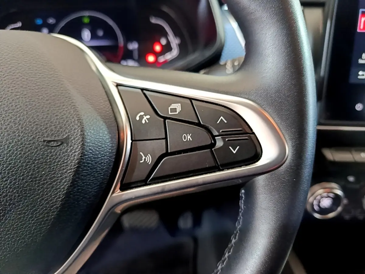 Gros plan sur les commandes multifonctions à droite du volant cuir du Renault Arkana blanc, tableau de bord en arrière-plan.