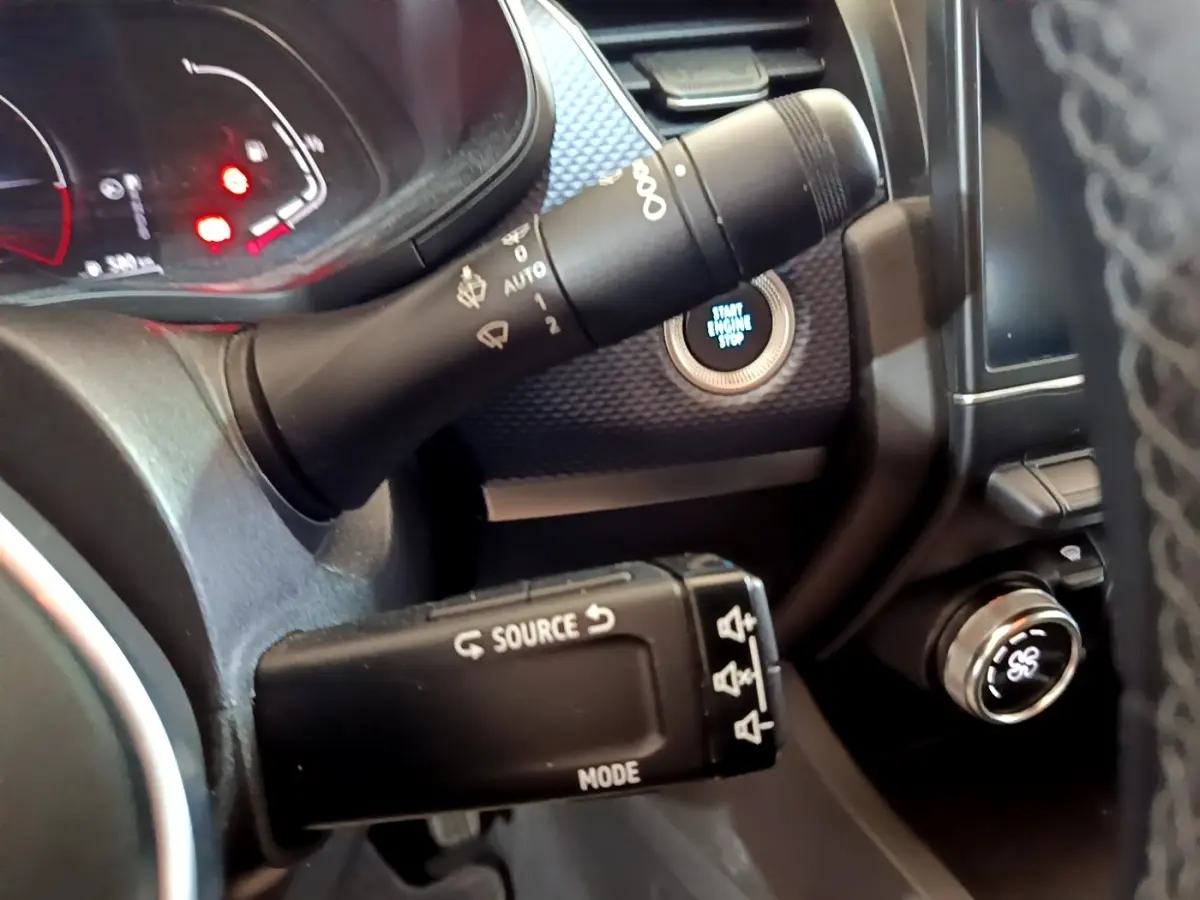 Gros plan sur la commande multifonction noire et le bouton start/stop éclairé du tableau de bord du Renault Arkana blanc.