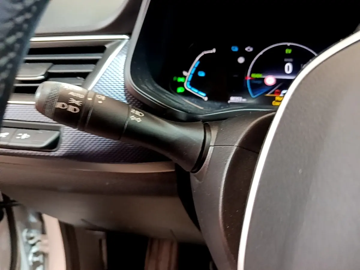 Gros plan sur la manette des phares et le combiné d'instruments numérique du tableau de bord du Renault Arkana blanc.