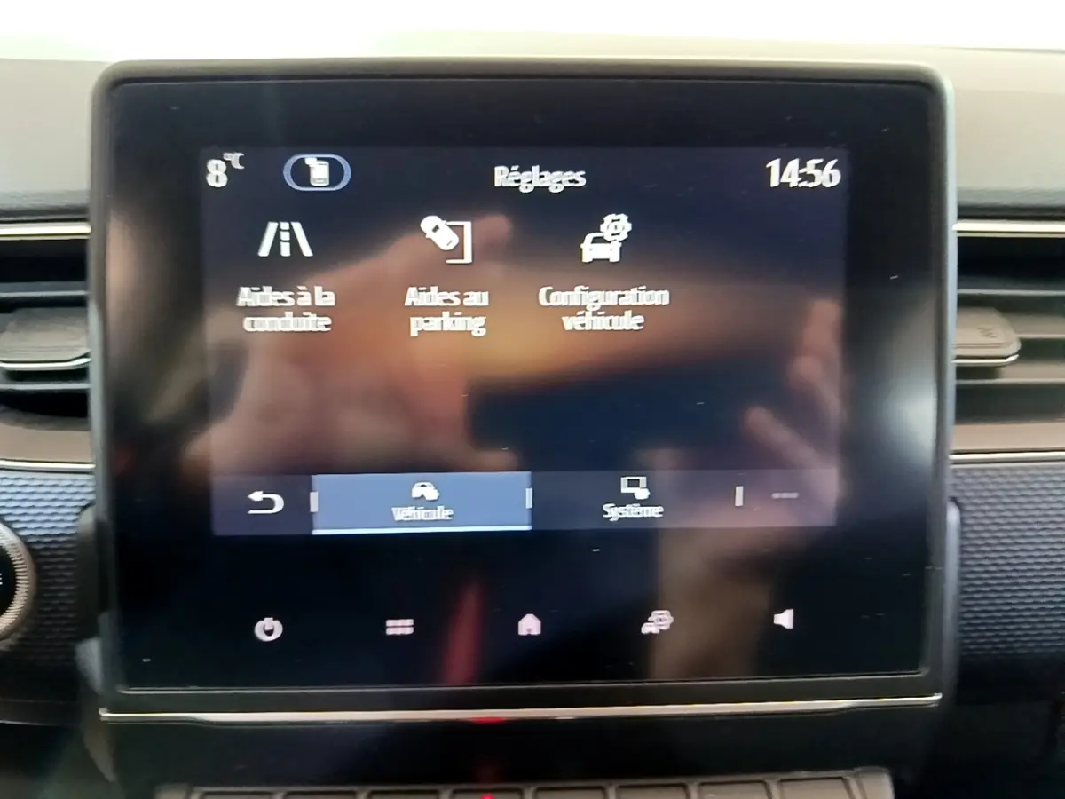 Écran tactile central du tableau de bord du Renault Arkana blanc, affichant les réglages d’aides à la conduite et au parking.